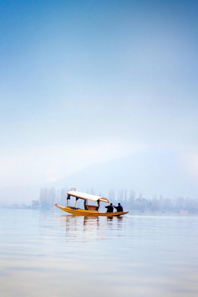 Serene boat ride on Dal Lake in Jammu, surrounded by mist and calm waters.