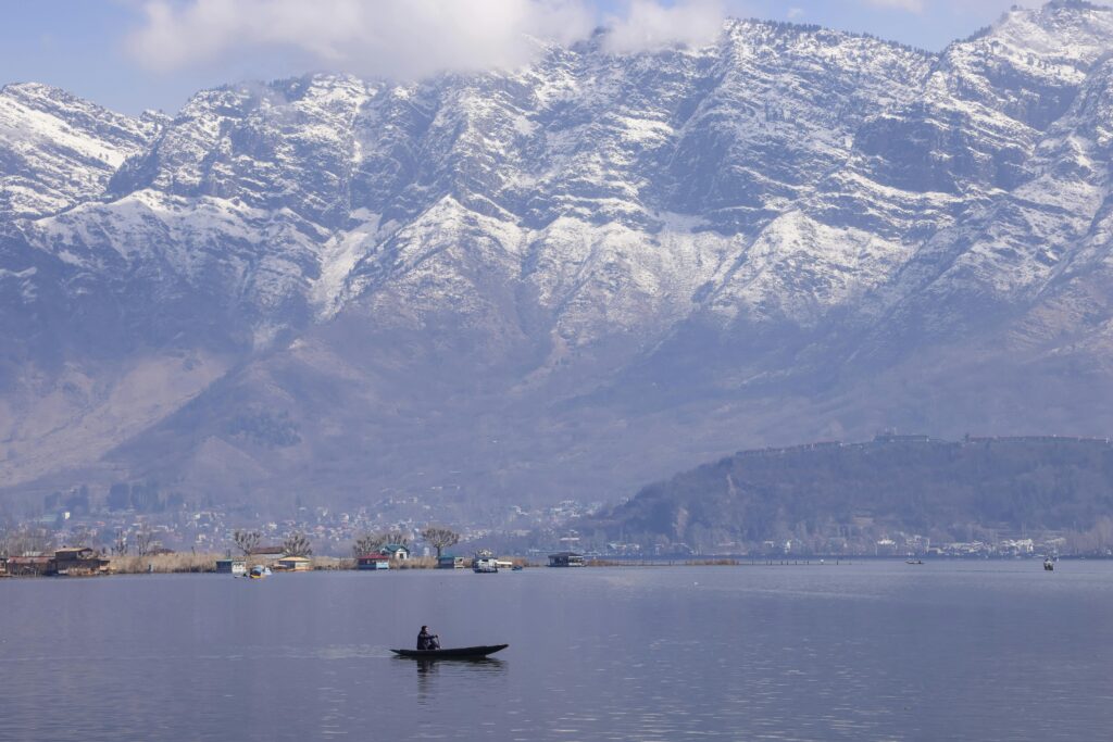 pexels-photo-25786569-25786569 Tranquil scene of a boat on Dal Lake with snow-capped Zabarwan mountains in Srinagar.